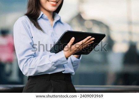 Young Asian business woman leader entrepreneur, professional manager holding digital tablet computer uon the street in big city on business center background.