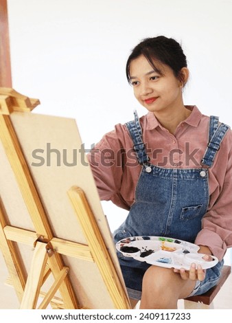 Happy young girl drawing with a paint palette and a paintbrush at home,painting artist.
