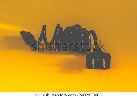 Black electric power outlet cable on yellow background.