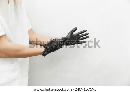 The cosmetologist puts on sterile black gloves and prepares to receive clients.