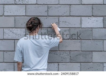 breaking the law: man with a spray paint can painting a wall outdoor, damaging the building 