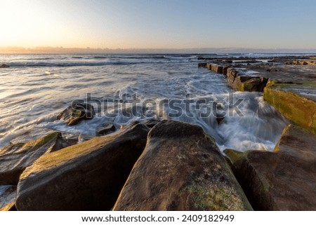 Sunrise at Merewether, Newcastle, NSW, Australia. Long exposure photography, seawater lapping the rocks.