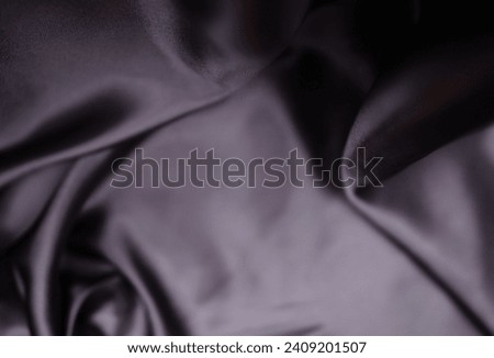 Shiny gray-black satin or silk fabric beautiful and luxurious It is an abstract background with a beautiful blurry, soft wave pattern.
