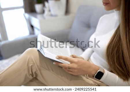 Beautiful woman reading a book on the sofa in the living room. Have a good time at home.