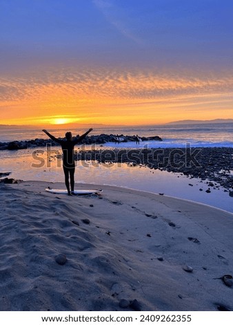 Surfer about to go for a sunrise. Surf session in Capitola, California. Big waves coming in. Royalty-Free Stock Photo #2409262355