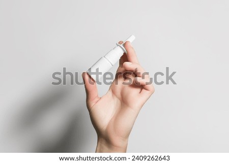 hand holding a white bottle with nasal spray Royalty-Free Stock Photo #2409262643