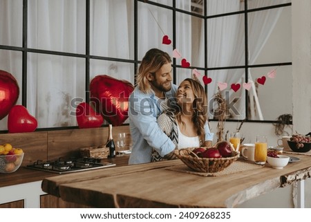 Happy young couple embracing while celebrating Valentines day with red balloons on background