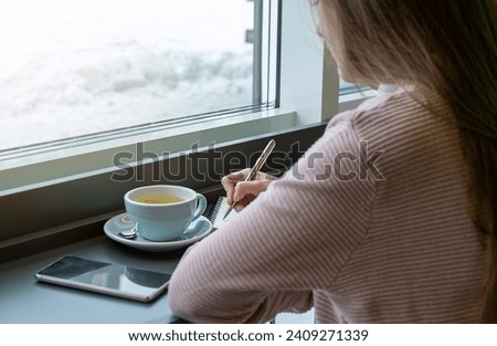 Woman is using pen writing Record Lecture note, Woman writing in coffee shop.
