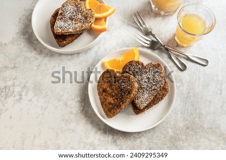 Sweet romantic breakfast for two; heart shaped wholegrain bread toasts and fresh orange slices table top view