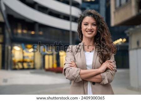 Happy smiling confident female leader businesswoman standing outside the modern office workplace looking at camera with arms crossed. Business successful executive concept. Portrait.