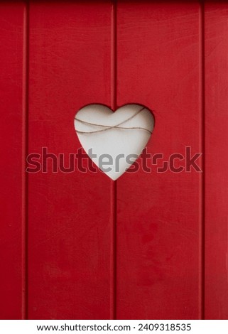 Vertical photo. Hole in shape of white heart in red wooden surface. Christmas market stall door. Valentine's day celebration concept, relationships, holiday of love, . Greeting card for lover. Wood
