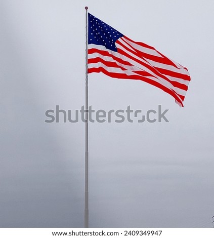 A large American flag waves across the sky 