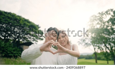 Young asia people happy lover flirt fall in love care trust hand sign tender symbol. Just married sweet time comfort asian couple life man woman relax smile showing finger heart shape look at camera.