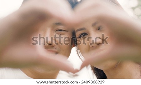 Young asia people happy lover flirt fall in love care trust hand sign tender symbol. Just married sweet time comfort asian couple life man woman relax smile showing finger heart shape look at camera.