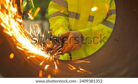 Close up hand Professional heavy industry workers wearing safety suits using angle grinders and metal pipe cutters. Royalty-Free Stock Photo #2409381353