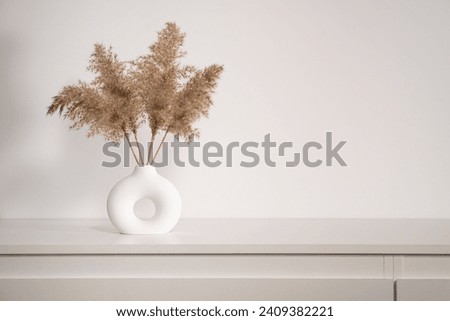 Dry autumn grass in a round vase on a white background Royalty-Free Stock Photo #2409382221