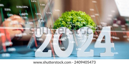 Businessman working at an office desk with a laptop, smartphone and 2024 plant. Forex chart.