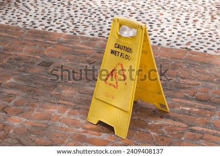 Sign showing warning of caution wet floor with brick floor, broken signage