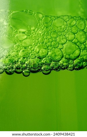 Closeup of beer bubbles from a green beer bottle.
