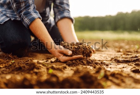 Close-up of a farmer's strong hands on a black field. The male hands of an agronomist sort through and check the quality of the soil. Concept of gardening, ecology.