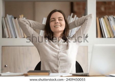 Calm Caucasian millennial female student lean back in chair at desk relax with eyes closed take break from studying, happy girl rest at workplace breathe fresh air enjoy peace, stress free concept Royalty-Free Stock Photo #2409450055