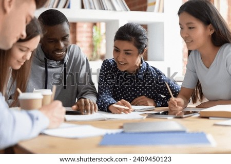 Motivated international young people sit at table brainstorm working on group project in classroom together, concentrated multiethnic students share ideas studying cooperating at teamwork meeting Royalty-Free Stock Photo #2409450123