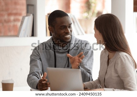 Motivated african American male student brainstorm share discuss ideas with female teammate, smart focused multiethnic millennial mates talk work study together using laptop, teamwork concept Royalty-Free Stock Photo #2409450135