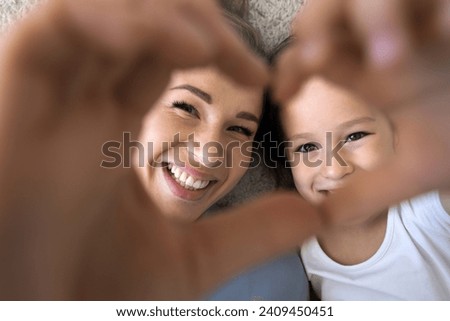 Close up shot daughter and loving mom showing symbol of affection, join fingers together look at camera through heart sign, feeling unconditional love, express support. Family ties, happy Mothers Day