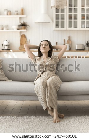 Peaceful woman rest on cozy sofa in living room with eyes closed, take deep breath fresh air, meditate, enjoy peace, no-stress, carefree single girl relaxing at home, fall asleep on couch at daytime Royalty-Free Stock Photo #2409450501