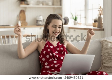 Happy young woman relish great, unbelievable on-line news, raise her arms enjoy online bet victory, feels excited get fantastic sell-out, huge discount offer, receive university admission acceptance Royalty-Free Stock Photo #2409450521