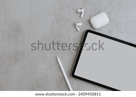 Creative process. Tablet pad with blank screen, pencil, wireless earphones on concrete background. Flat lay, top view social media, web, online shop template with mockup copy space