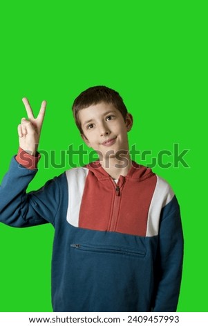 boy over isolated green background smiling and showing victory sign