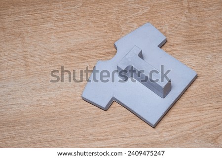 Unique and minimal clothing concept image. Letter T and t-shirt made of concrete material on wooden background.