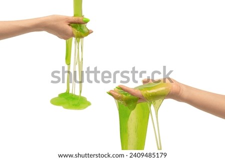Green slime toy in woman hand with green nails isolated on a white background.  Royalty-Free Stock Photo #2409485179