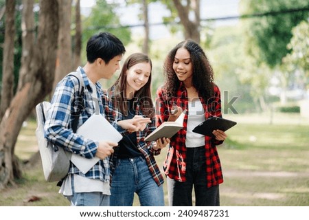 Three young college students is reading a book while relaxing sitting on grass in a campus park with her friends. Education concept in morning Royalty-Free Stock Photo #2409487231