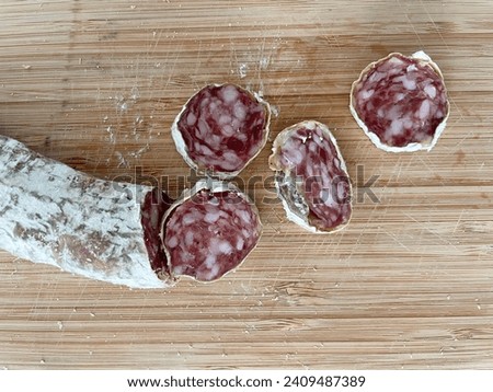 close up top view photo of dry meat slices of pork salami peperoni food on a wood board in a kitchen