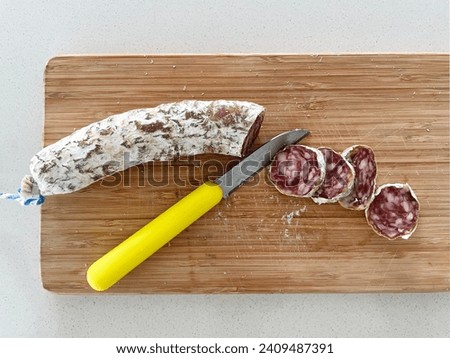 close up top view photo of dry meat slices of pork salami peperoni food on a wood board in a kitchen