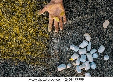 Ukrainian girl, child shows dirty, smeared hands, palms with yellow chalk after drawing a picture on the asphalt. Photography, top view, childhood concept.