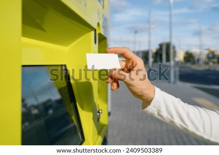Selective focus on woman hand showing ticket for public transport near atm. Blurred urban background. Paper document that allowing travel in bus, tram, trolleybus, train. Copy space Royalty-Free Stock Photo #2409503389