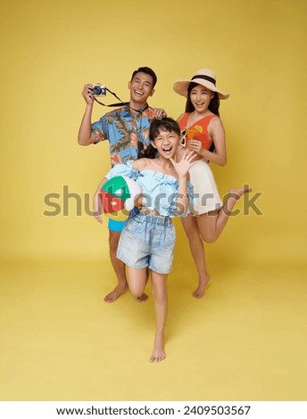 Happy fun asian family vacation portrait. Father, mother and daughters enjoying summer beach isolated on yellow studio background.