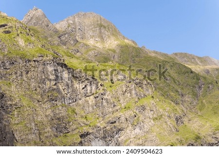 The barren rocky mountains in the middle of the countryside , Europe, France, Occitanie, Hautes-Pyrenees, in summer on a sunny day.