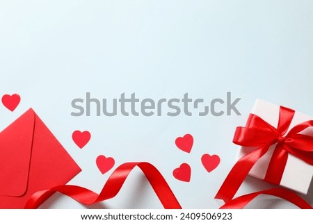 Beautiful present and red paper envelope and Valentines hearts on blue background. Flat lay, top view. Romantic love letter for Valentine's day concept. Royalty-Free Stock Photo #2409506923