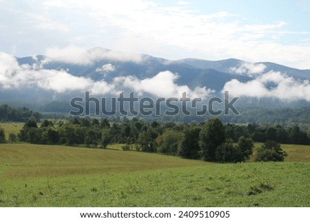 Cades Cove in Great Smoky Mountains National Park - Green Meadow in Foreground Leading to Cloud-Covered Mountain Peaks in Background