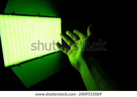 Green neon light. Professional photo or video lighting. SRGB Led-panel on tripod for home or studio shooting. Adjusting light equipment.