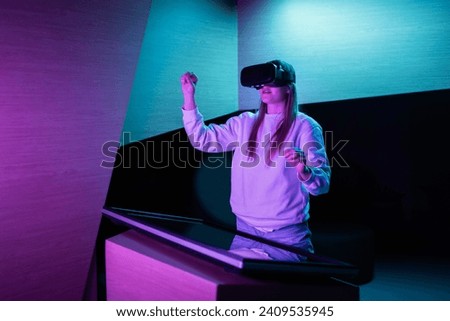 Girl in a virtual reality headset standing in front of a touch screen display making hand gestures in the air. Hand tracking concept.