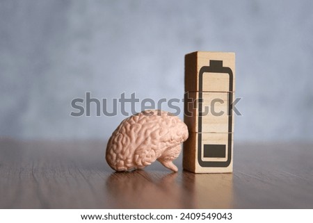 Closeup image of brain and wooden blocks with low energy battery icon. Exhausted, tired and burnout concept.
