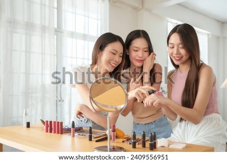 Portrait of Three Asian Women applying body cream. Teenage Girl models with beautiful face having Fun. Happy young people. Group of female friends at home indoor. Skin care.