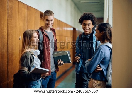 Multiracial group of happy high school students communicating in a hallway. Royalty-Free Stock Photo #2409569859