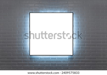 frame 1:1 hanging on a brick wall illuminated wit LED light