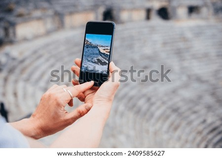 Person takes a mobile photo of ruins of ancient Greek-Roman theatre of Myra in Demre, Turkey.